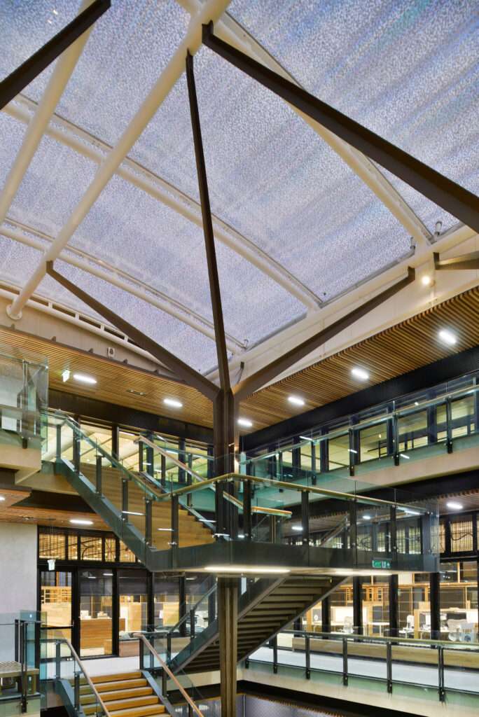ETFE Australia: Global Change Institute in Brisbane features a 497 m² ETFE atrium roof with three-layer cushions and printed grid foils, combining natural light and heat control for a zero-energy, zero-carbon educational facility.
